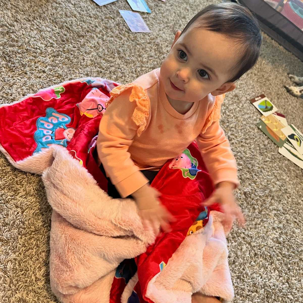 Child sitting on a colorful blanket on a carpeted floor